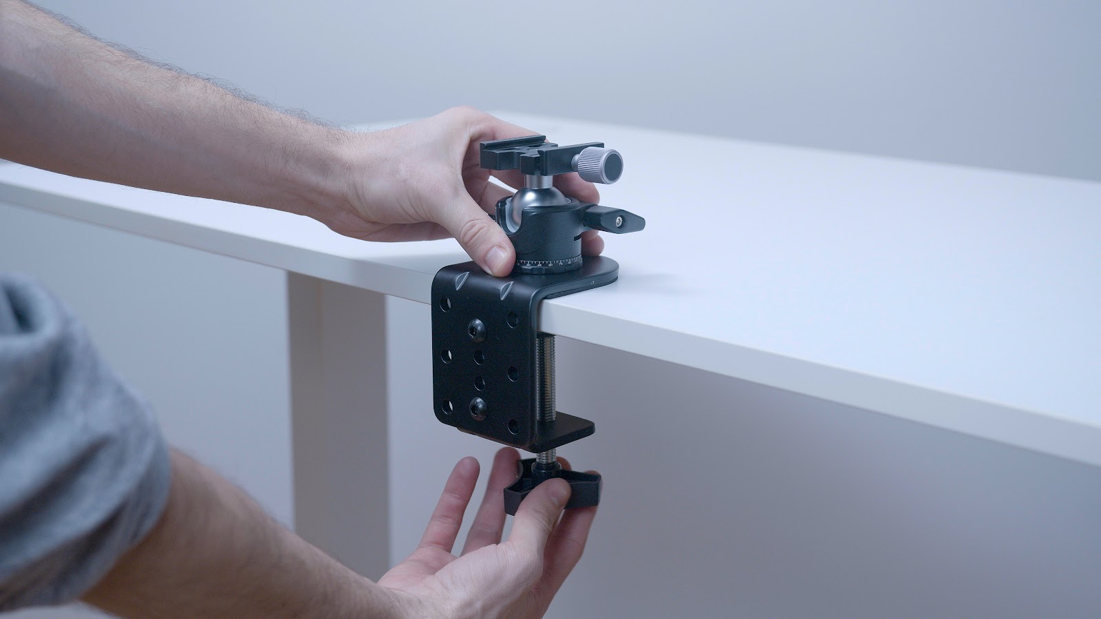 A hand placing a gimbal mount of a desk